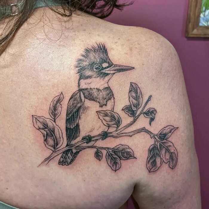 Nature tattoo featuring a bird perched on a branch, celebrating the human-Earth bond.