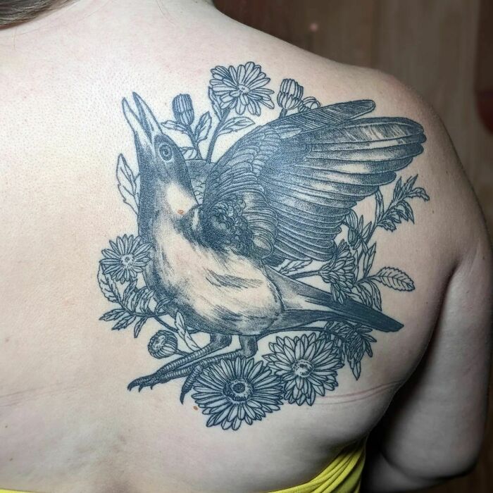 Bird and floral nature tattoo on back, symbolizing the human-Earth bond.