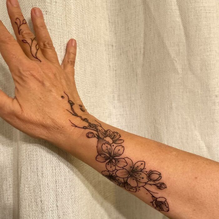 Floral nature tattoo on forearm, showcasing intricate blossom design celebrating human-earth connection.