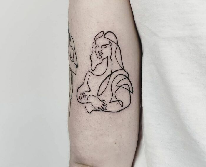 Single-line tattoo of an abstract face on an arm.