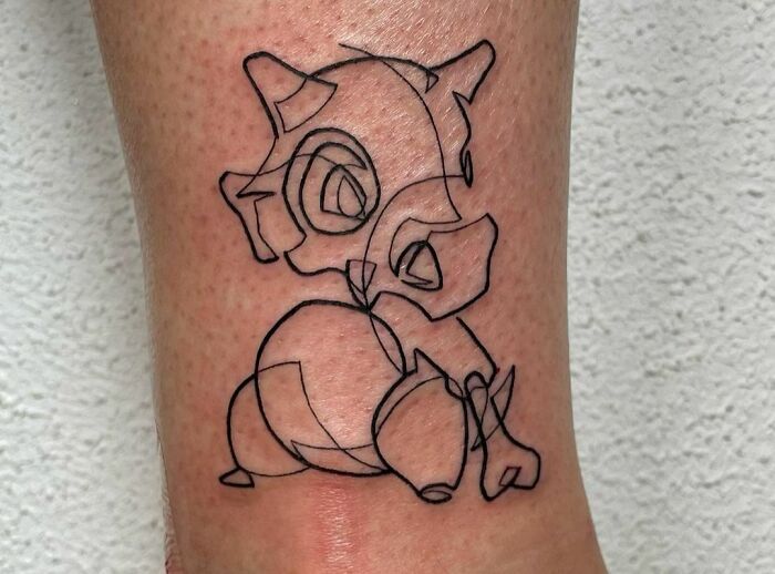 Single-line tattoo of an abstract character on a person's skin.