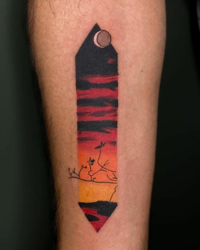 Tattoo of a landscape at sunset with a crescent moon and branches, showcasing nature's beauty.