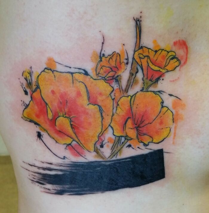Watercolor tattoo of vibrant orange flowers with black brushstroke detail, showcasing ethereal artistry.