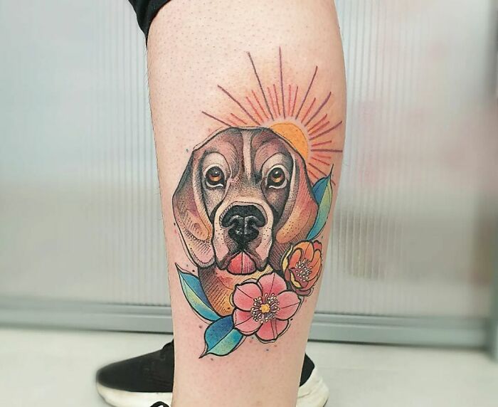 Watercolor tattoo of a dog with flowers and sun on a leg, showcasing ethereal artistry.
