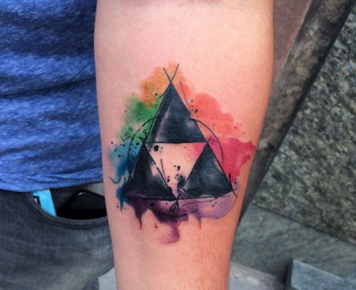 Watercolor tattoo featuring a geometric design with vibrant rainbow hues and abstract splashes.