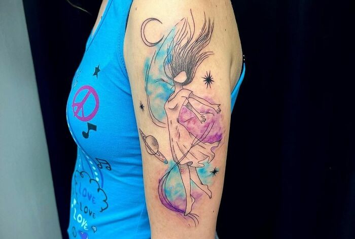 Ethereal watercolor tattoo of a dancing figure with celestial elements on an arm.