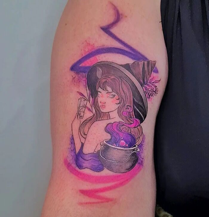 Ethereal watercolor tattoo of a witch with a cauldron and purple hues on an arm.