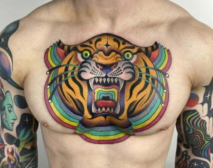Colorful tiger tattoo on chest with vibrant patterns, showcasing bold animal art.