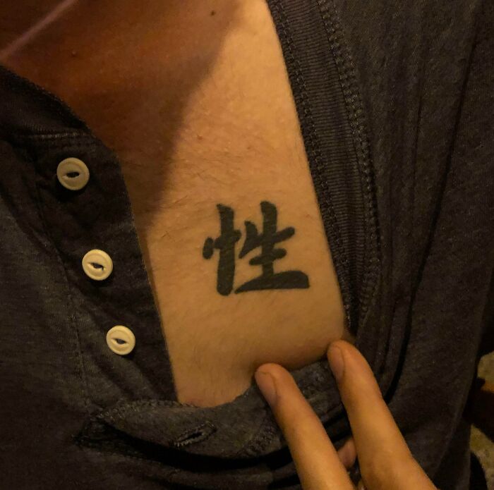 A funny tattoo with a Chinese character on a person's chest, partially covered by a shirt.