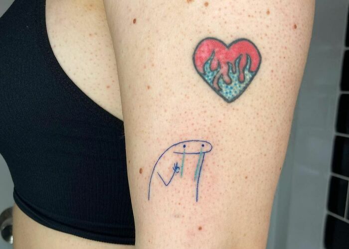 Funny tattoos featuring a heart with flames and a simple abstract face drawing on an arm.
