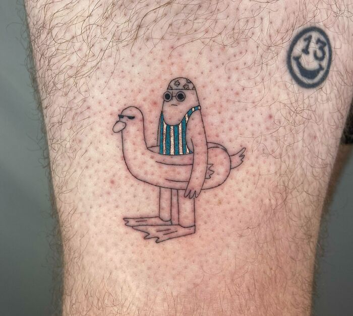 Humorous tattoo of a cartoon character wearing a duck-shaped float, designed to put a smile on your face.