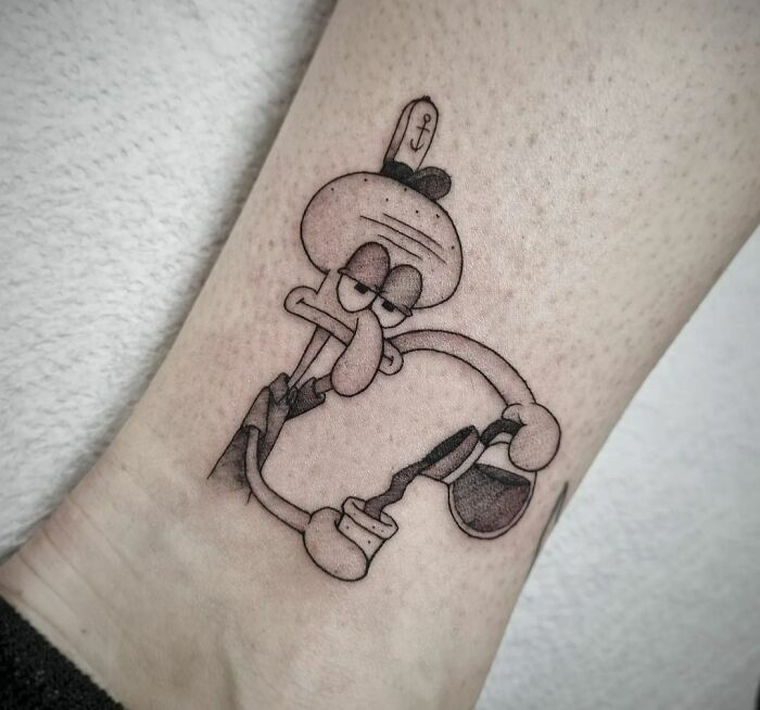 Funny tattoo of a cartoon character holding a coffee pot, inked on forearm.