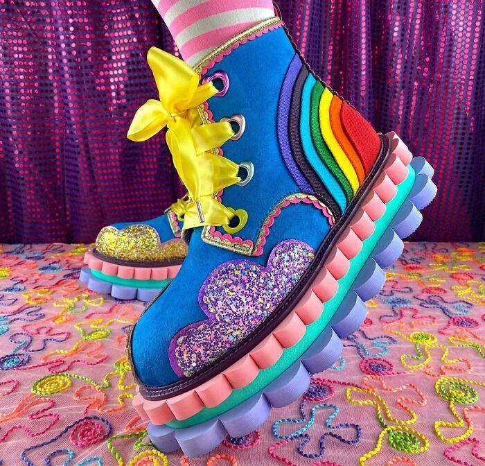 Colorful weird shoes with rainbow patterns, yellow laces, sparkly heart designs, and thick multicolored soles.