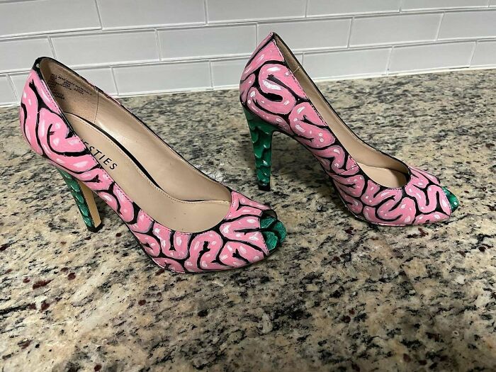 Weird shoes with pink brain design on a speckled granite surface.