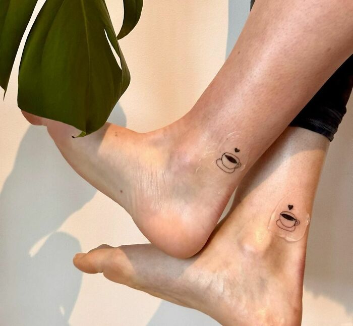Minimalist BFF tattoos of coffee cups with hearts on ankles, symbolizing friendship.