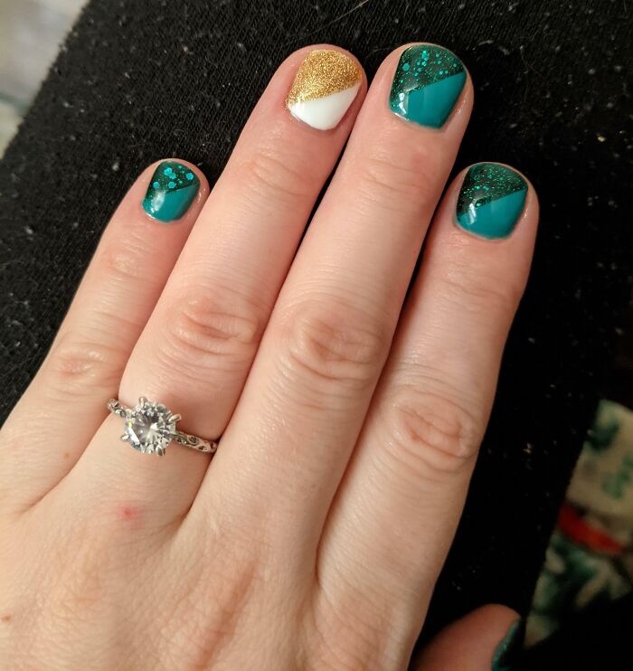 Hand with teal and gold glitter nail art designs on short nails, showcasing creative nail art ideas and styles.