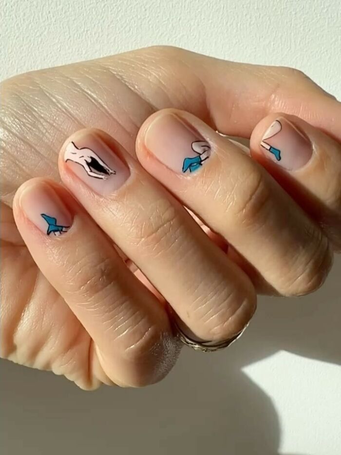 Close-up of hands showing minimalistic nail art ideas with small abstract figures on natural nails.