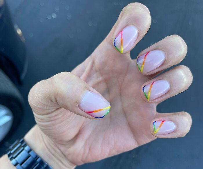 Hand with nails featuring minimalist rainbow nail art design on a neutral base, showcasing creative nail art ideas.