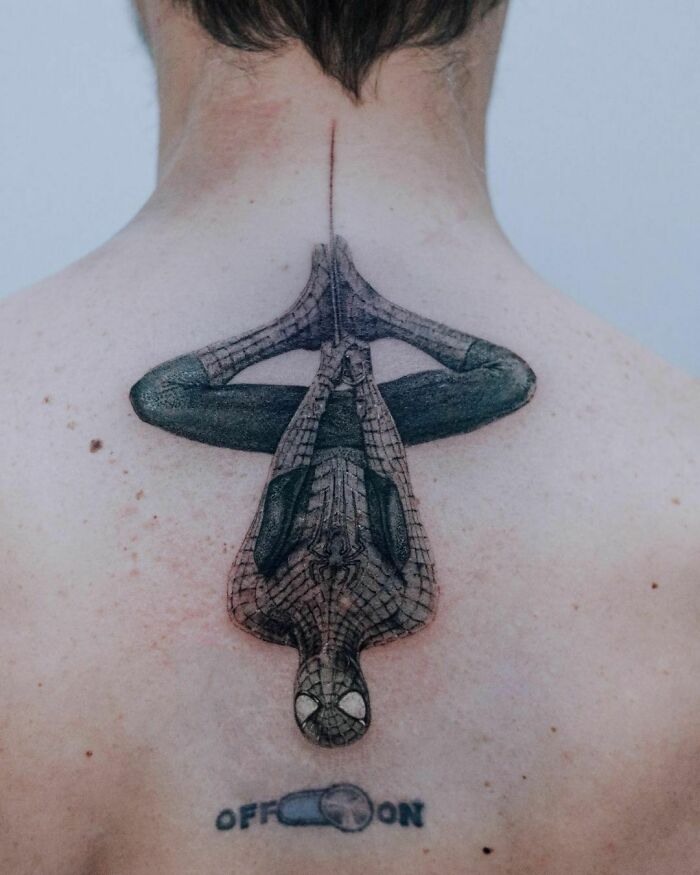 Marvel tattoo of Spider-Man hanging upside down on a person's back, showcasing intricate superhero design.