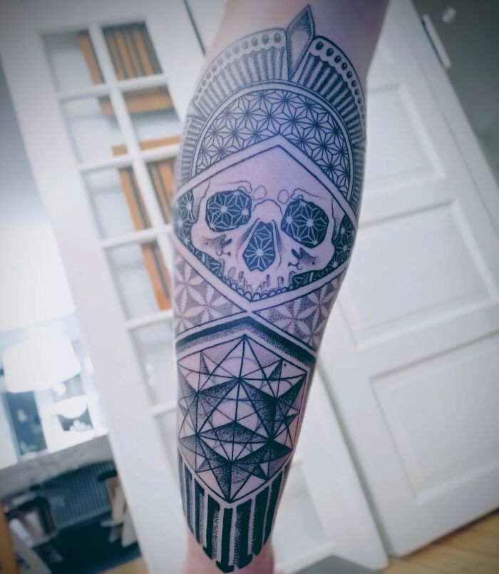 Geometric tattoo on forearm featuring intricate shapes and skull design, showcasing creativity and unique forms.