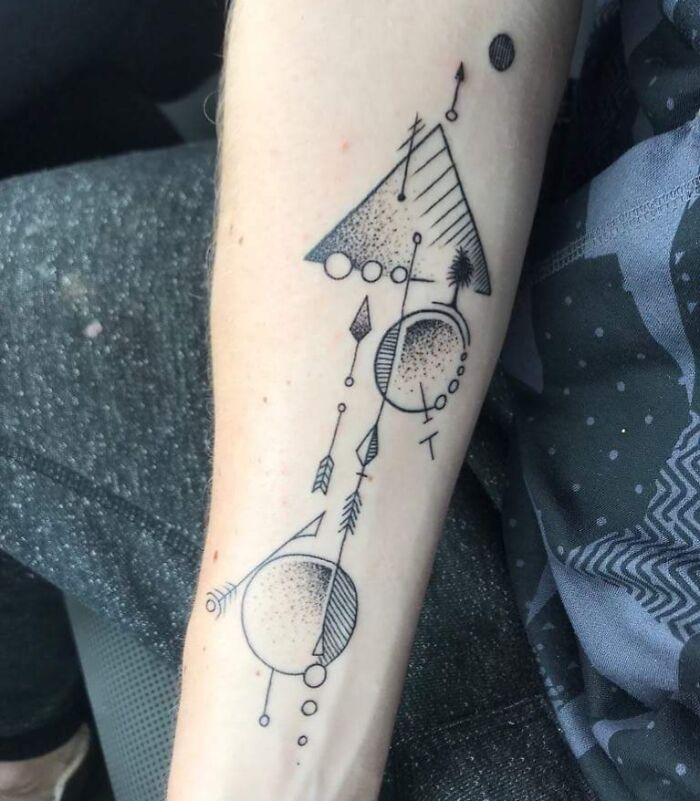 Geometric tattoo featuring triangles, circles, and arrows on a forearm, showcasing creative forms and shapes.