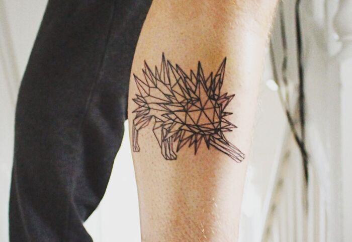 Geometric tattoo of a hedgehog on a person's arm, featuring intricate triangular patterns.