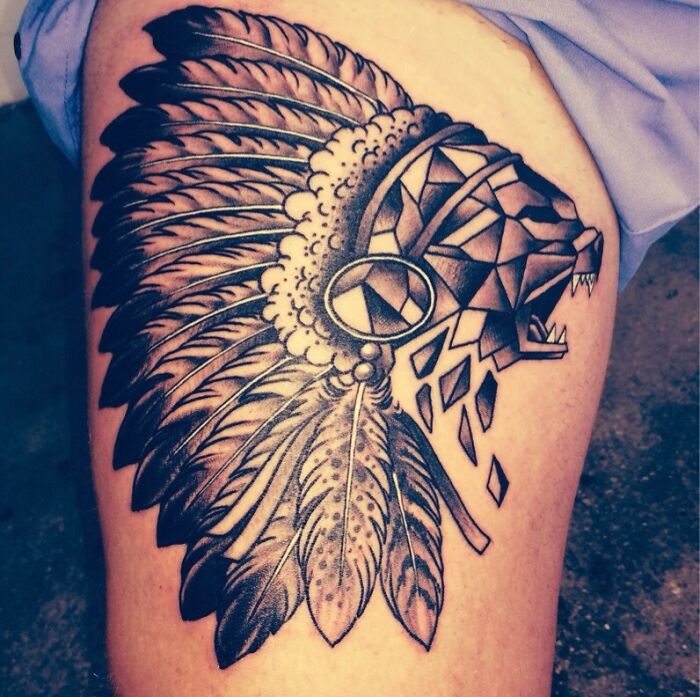 Geometric tattoo of a bear with tribal headdress, showcasing intricate design on bare skin.