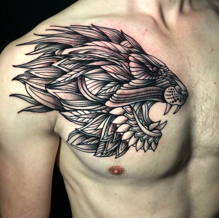 Geometric tattoo design of a lion's head on a man's chest, emphasizing shapes and creativity.