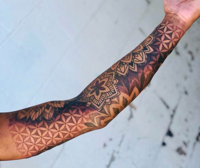 Arm with geometric tattoo designs showcasing intricate shapes and forms with creative patterns.