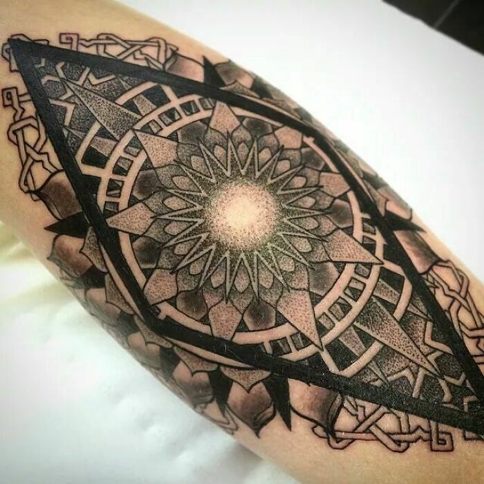 Intricate geometric tattoo with circular mandala design on arm, showcasing complex patterns and bold lines.