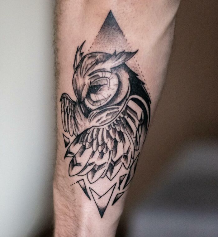 Geometric tattoo of an owl on a forearm featuring intricate shapes and forms.