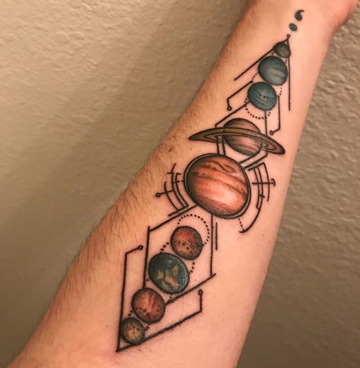Geometric tattoo featuring planets in a solar system design on a forearm.