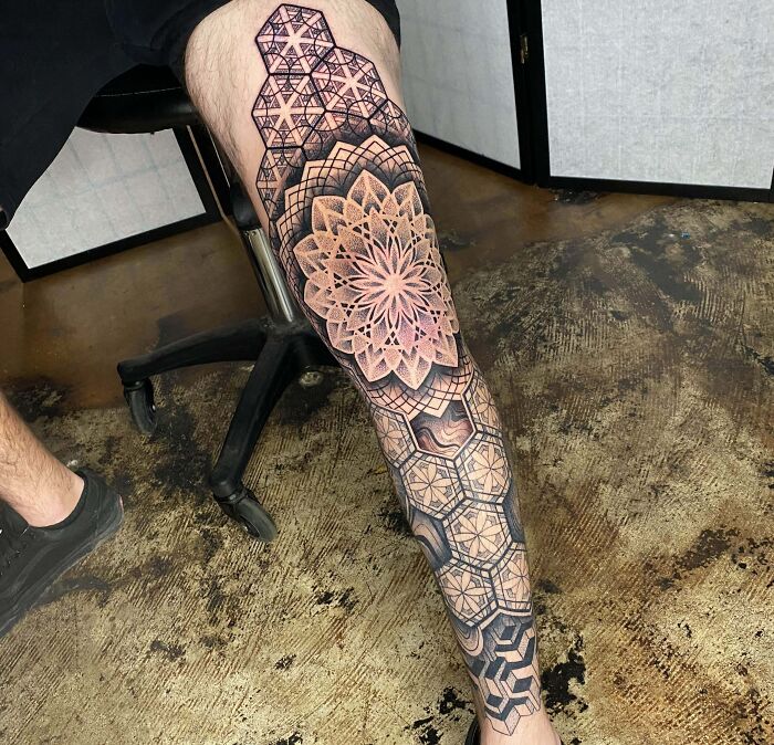Detailed geometric tattoo design on a person's leg, featuring intricate patterns and shapes.