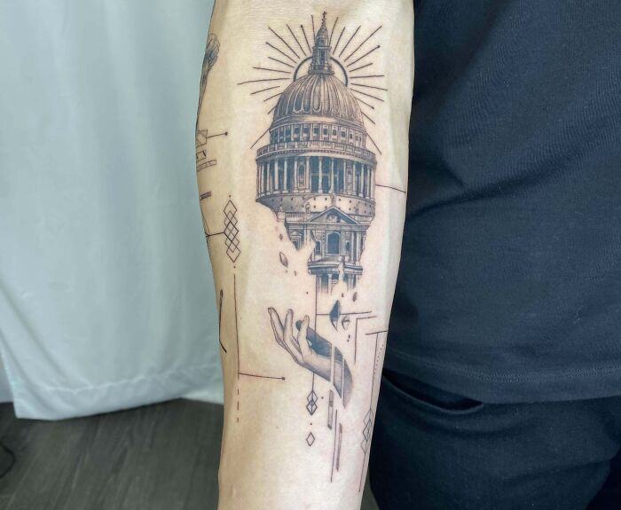 Geometric tattoo of a hand beneath a dome structure on an arm, featuring intricate linework and patterns.