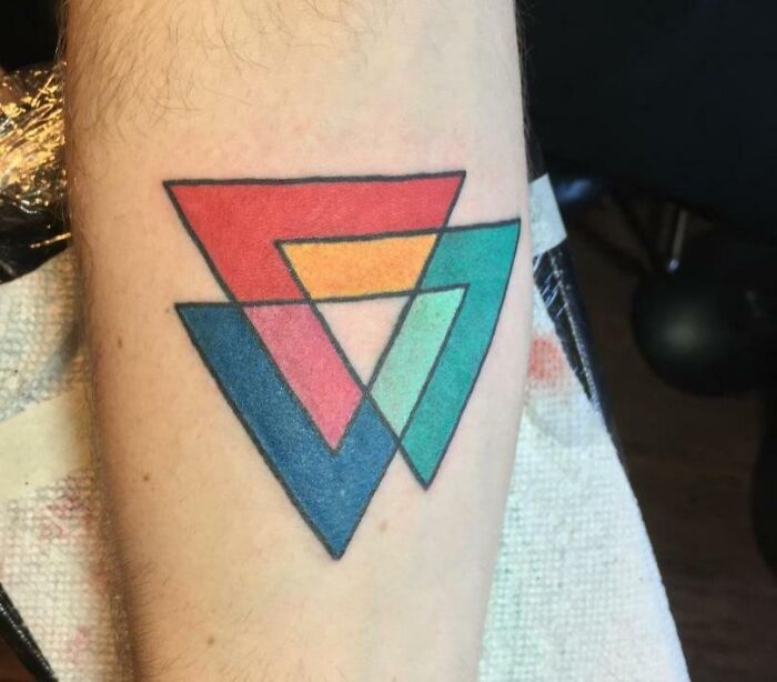 Geometric tattoo design on arm featuring colorful interlocking triangles.