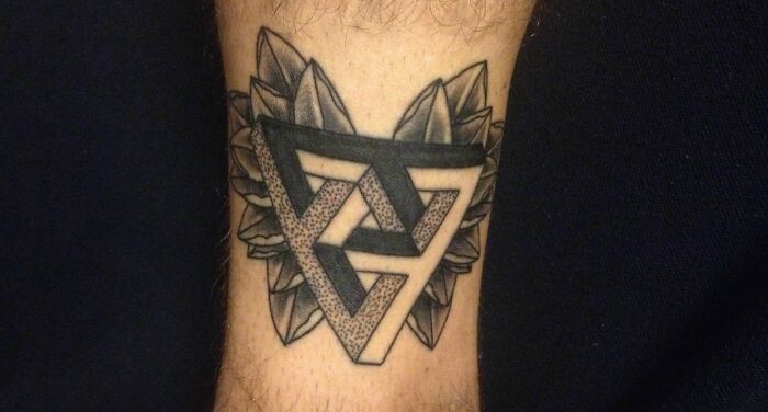 Geometric tattoo design featuring interlocking triangles and leaf motifs on an arm.