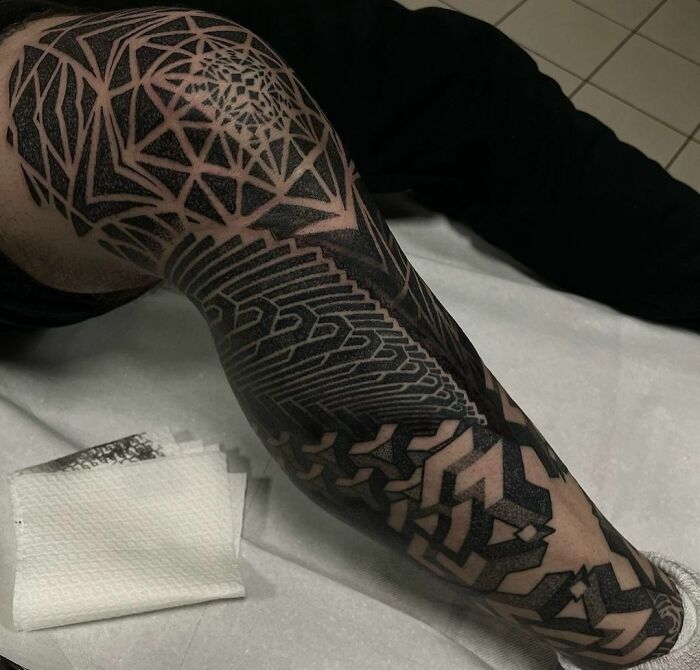 Intricate geometric tattoo design covering an arm with detailed patterns and shapes.