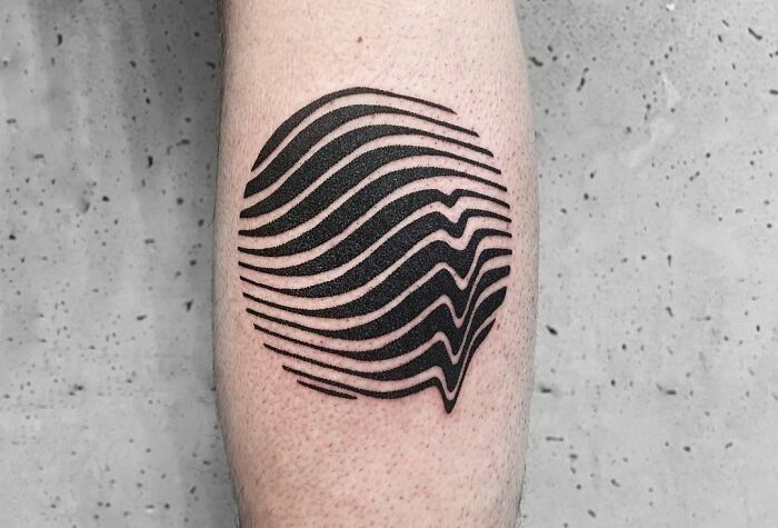 Geometric tattoo with black, wavy lines forming a circle on forearm.