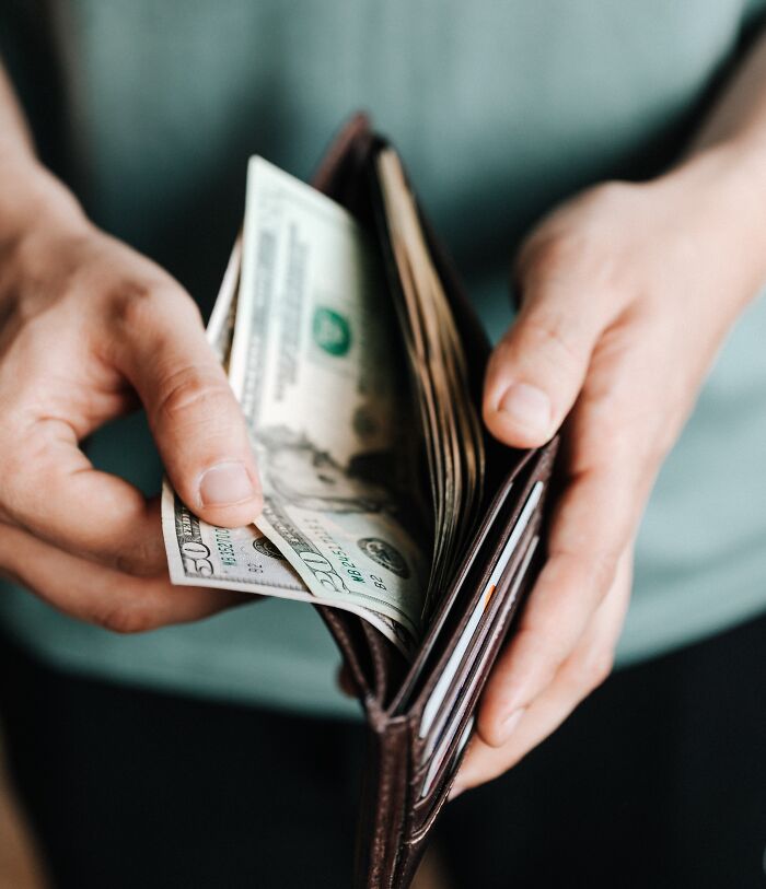 Person Counting Money In His Wallet 