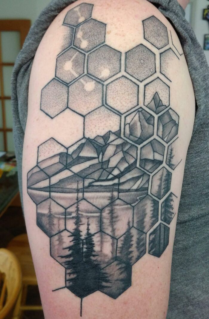 Geometric tattoo with hexagons and mountain landscape on the arm, blending natural scenery with geometric art.