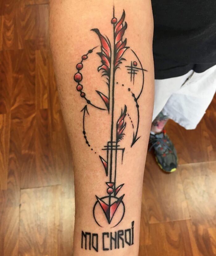 Arm tattoo with geometric designs and the text "MO CHROI," featuring abstract shapes in red and black.