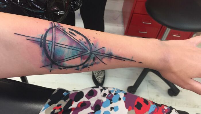 Geometric tattoo design on a forearm featuring intricate shapes and colorful forms.