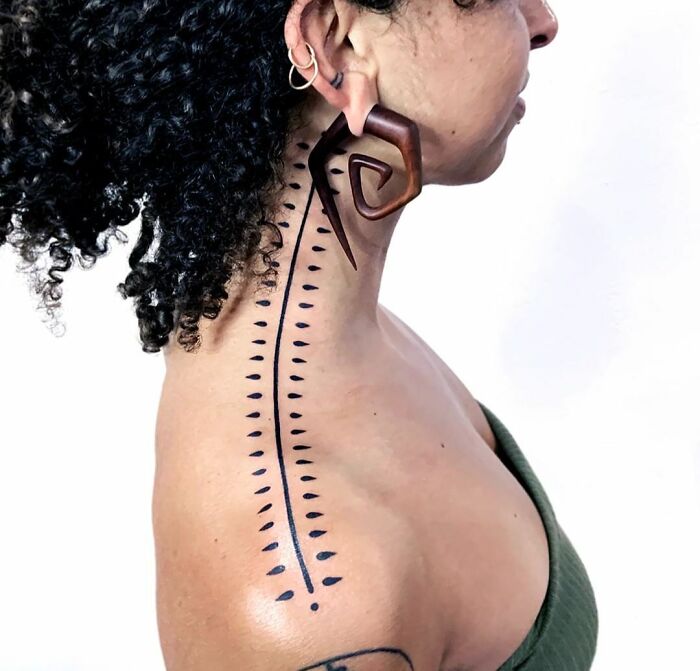 Geometric tattoo with dots and lines on a woman's neck and shoulder.