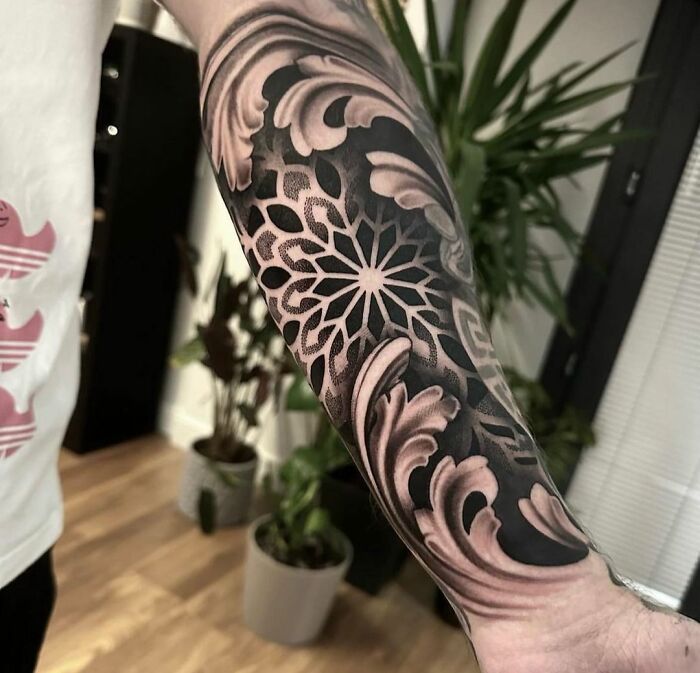 Forearm showcasing a detailed geometric tattoo design with floral patterns.