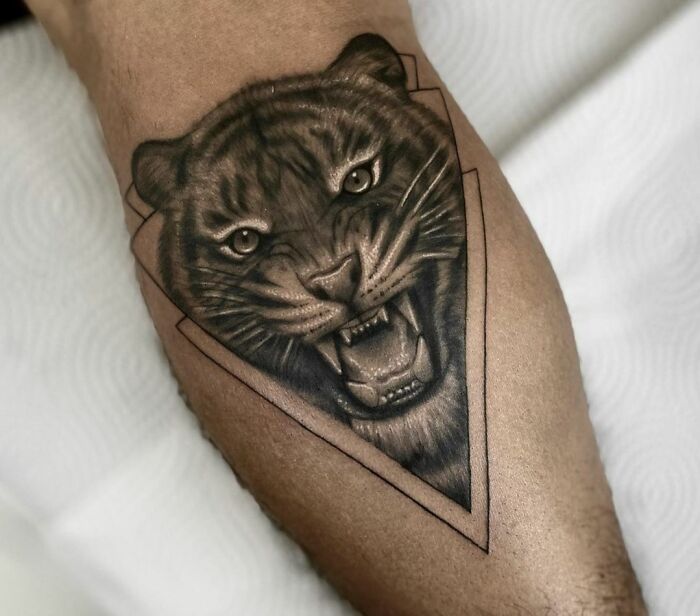 Geometric tattoo of a roaring lion on a forearm, showcasing bold creativity.