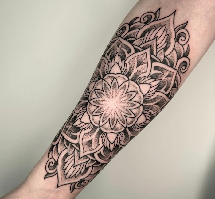 Geometric tattoo on forearm with intricate mandala design and black ink detailing.