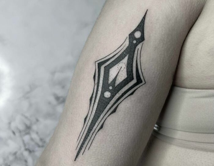 Geometric tattoo design on a forearm featuring sharp lines and abstract shapes.