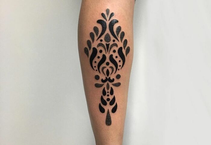 Geometric tattoo design with intricate black patterns on a leg.