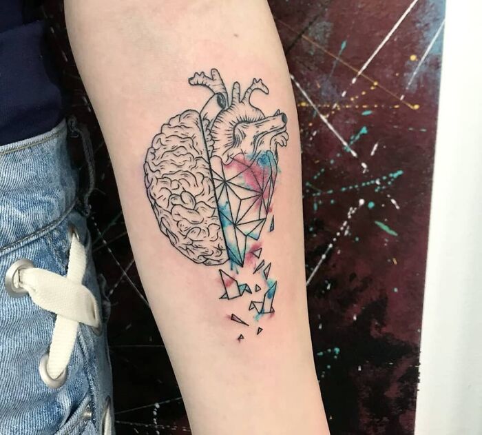 Geometric tattoo of a brain and heart with colorful shattered patterns on an arm.