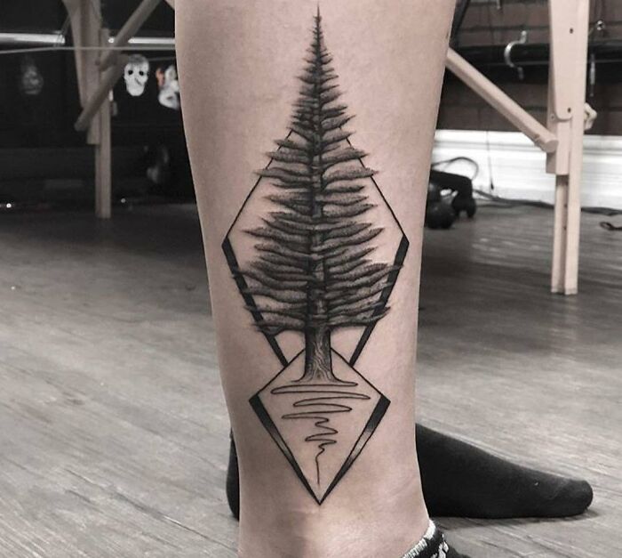 Geometric tattoo of a tree within diamond shapes on a calf, showcasing intricate linework and symmetry.